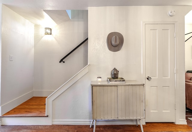 stairway with hardwood / wood-style flooring and radiator heating unit