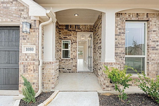 view of exterior entry featuring brick siding and a porch