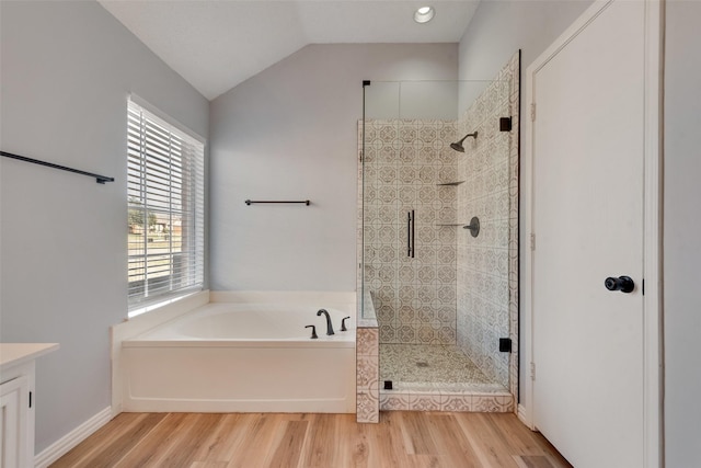 bathroom featuring shower with separate bathtub, vanity, hardwood / wood-style flooring, and lofted ceiling