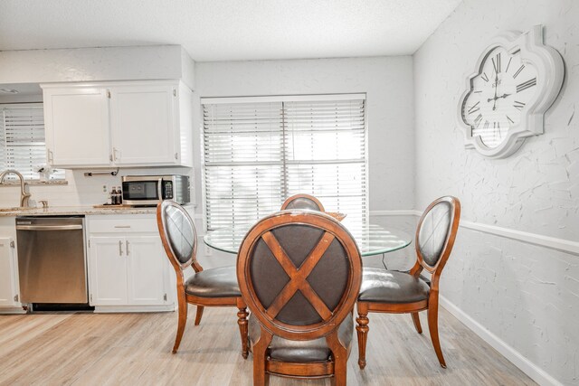 dining room with a textured ceiling, sink, and light hardwood / wood-style flooring