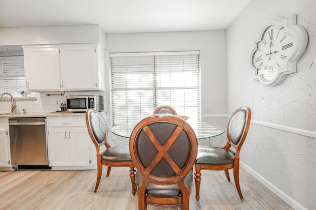 dining area with sink, a textured ceiling, and light wood-type flooring