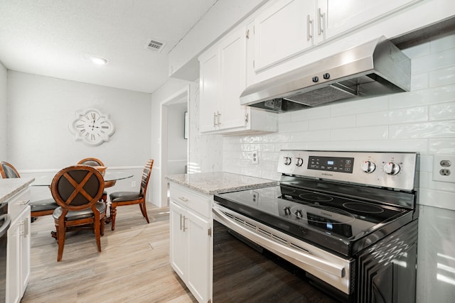 kitchen featuring tasteful backsplash, light stone counters, stainless steel electric range oven, light hardwood / wood-style flooring, and white cabinetry