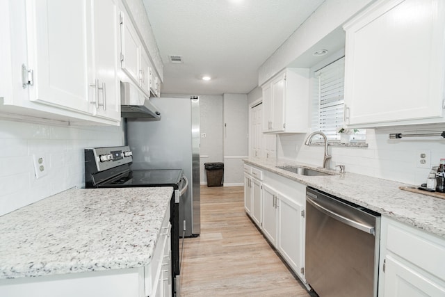 kitchen with white cabinets, sink, appliances with stainless steel finishes, and light hardwood / wood-style flooring