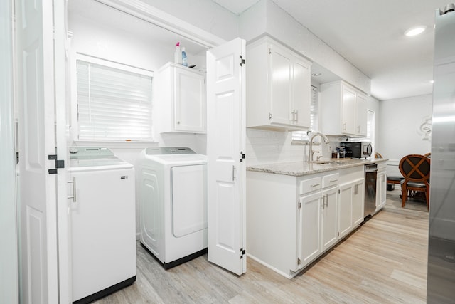 laundry area with washer and dryer, sink, and light hardwood / wood-style flooring