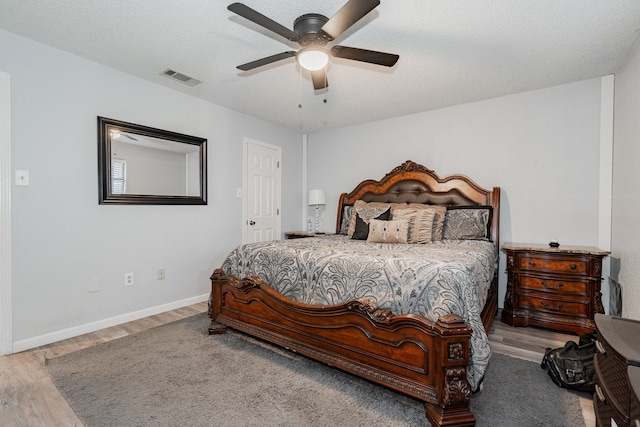 bedroom with ceiling fan, a textured ceiling, and light wood-type flooring