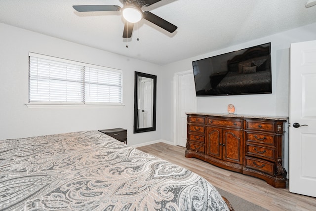 bedroom with ceiling fan, a textured ceiling, and light wood-type flooring