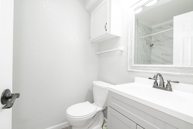 bathroom with a tile shower, vanity, and toilet