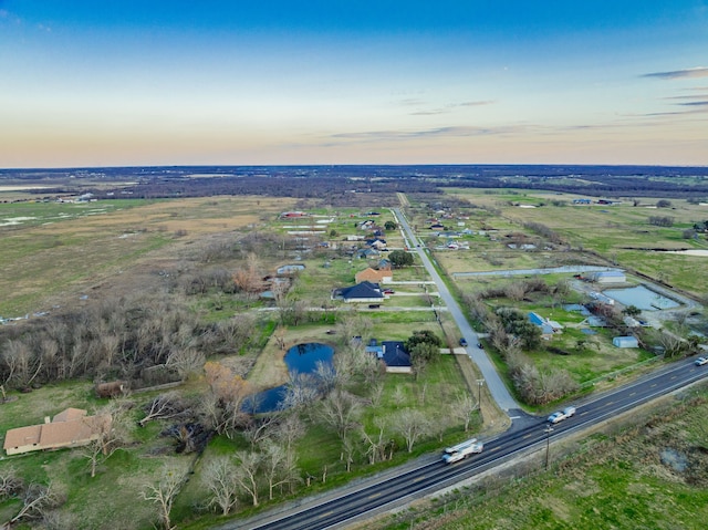 aerial view at dusk featuring a water view