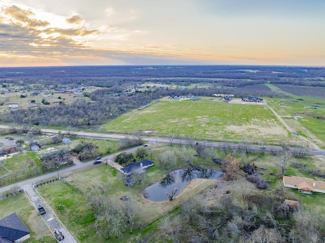 aerial view at dusk featuring a rural view and a water view