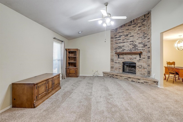 carpeted living room featuring vaulted ceiling, ceiling fan with notable chandelier, and a fireplace