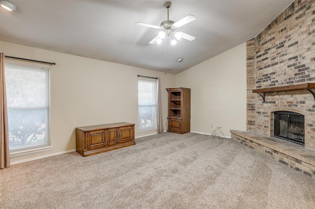 unfurnished living room with light carpet, a brick fireplace, vaulted ceiling, and ceiling fan