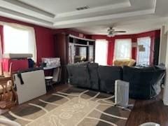 living room with ceiling fan and a tray ceiling