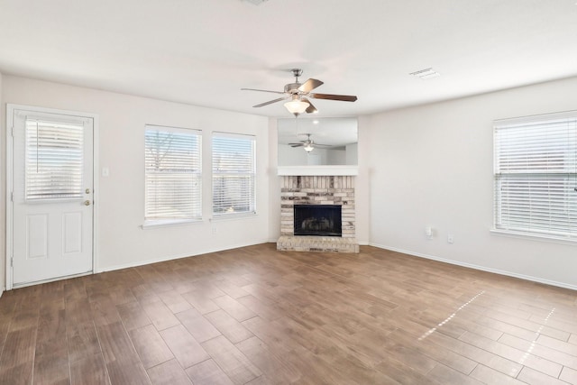 unfurnished living room with a brick fireplace, plenty of natural light, and wood-type flooring