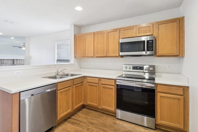 kitchen featuring sink, ceiling fan, stainless steel appliances, light hardwood / wood-style floors, and kitchen peninsula