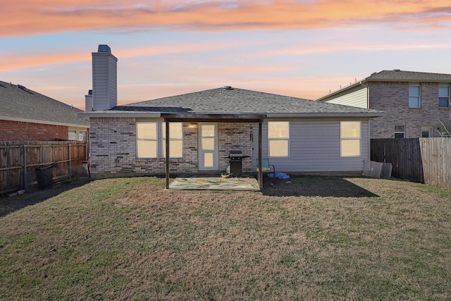 back house at dusk with a yard and a patio area