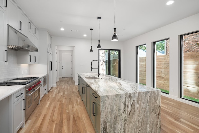 kitchen with pendant lighting, a spacious island, decorative backsplash, light stone countertops, and white cabinetry