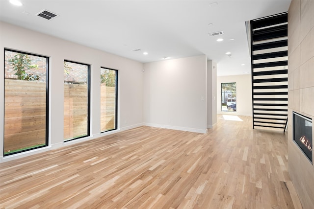 empty room with a fireplace, plenty of natural light, and light hardwood / wood-style flooring