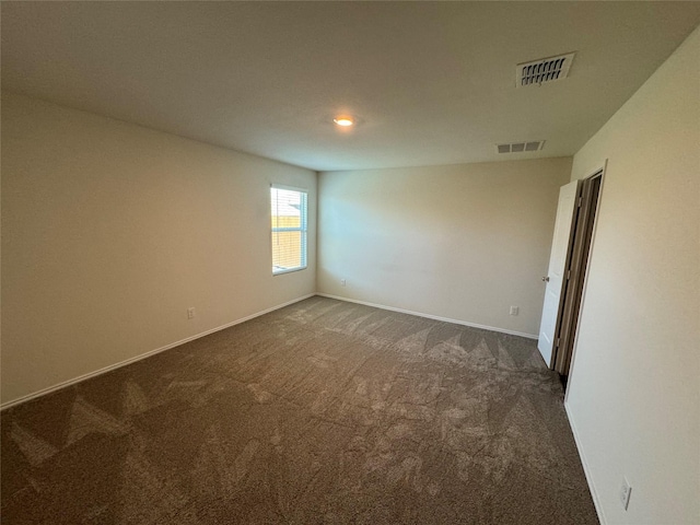 spare room featuring dark carpet