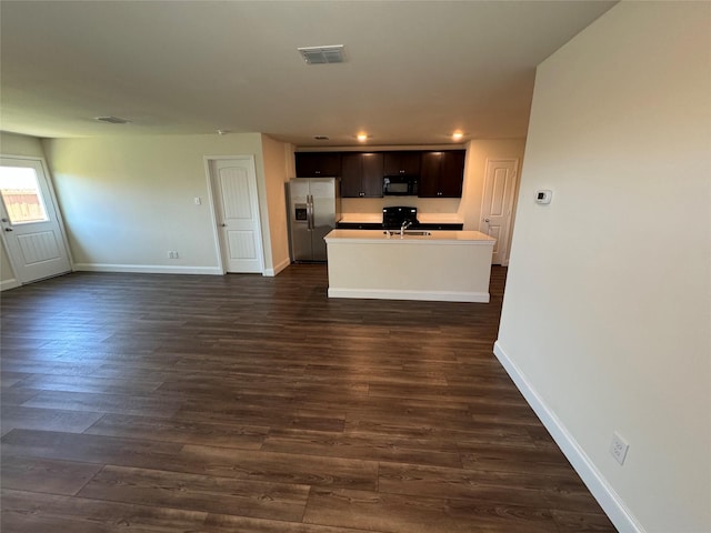 kitchen with dark brown cabinetry, stainless steel fridge with ice dispenser, dark hardwood / wood-style floors, stove, and a kitchen island with sink