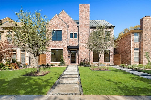 view of front of home with a standing seam roof, brick siding, metal roof, and a front lawn