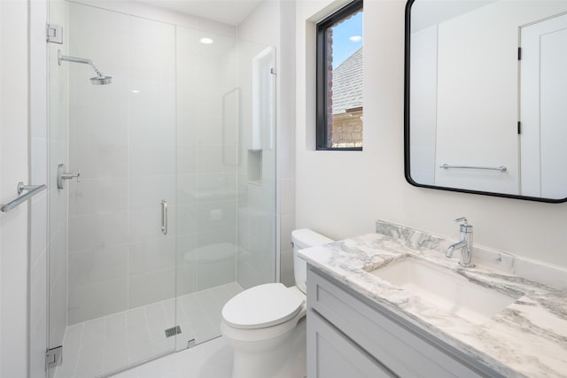 bathroom featuring vanity, toilet, and a shower with door