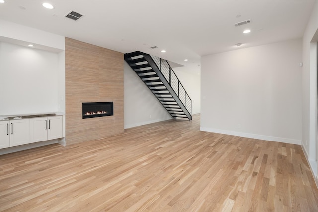 unfurnished living room with light hardwood / wood-style flooring and a tiled fireplace