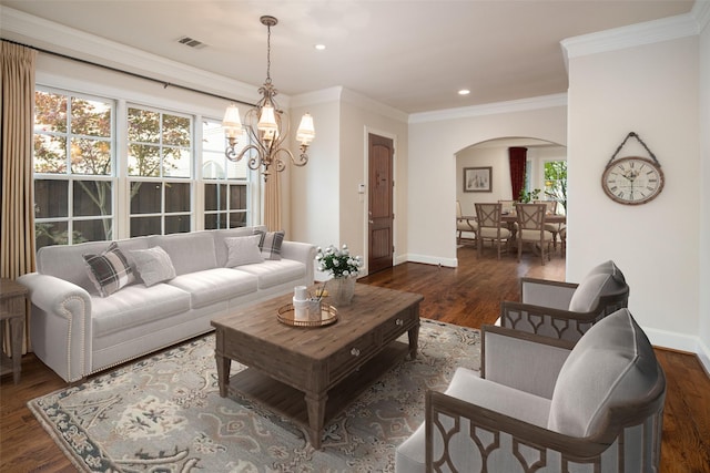 living room with crown molding, dark wood-type flooring, and an inviting chandelier