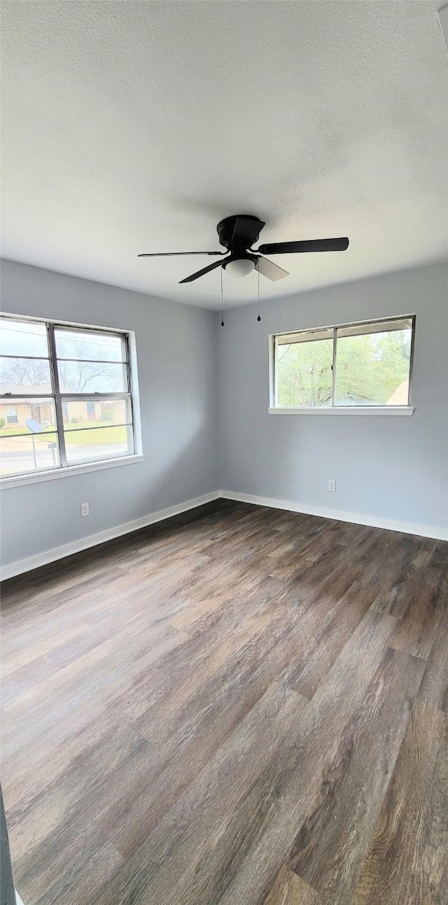 empty room with plenty of natural light, dark wood finished floors, and baseboards