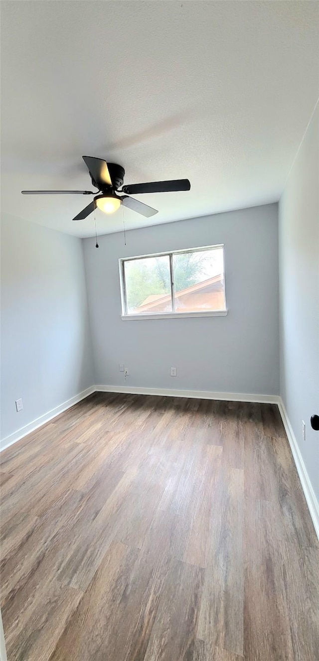 empty room featuring ceiling fan, baseboards, and wood finished floors