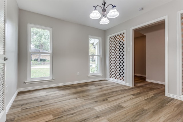 empty room with light hardwood / wood-style flooring and an inviting chandelier