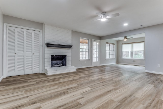 unfurnished living room featuring light hardwood / wood-style flooring, a brick fireplace, and ceiling fan