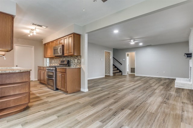 kitchen with ceiling fan, sink, stainless steel appliances, backsplash, and light wood-type flooring