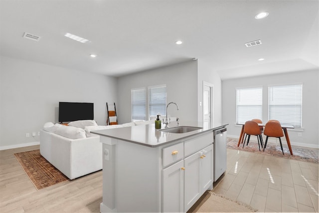 kitchen with white cabinetry, sink, light hardwood / wood-style flooring, stainless steel dishwasher, and a kitchen island with sink