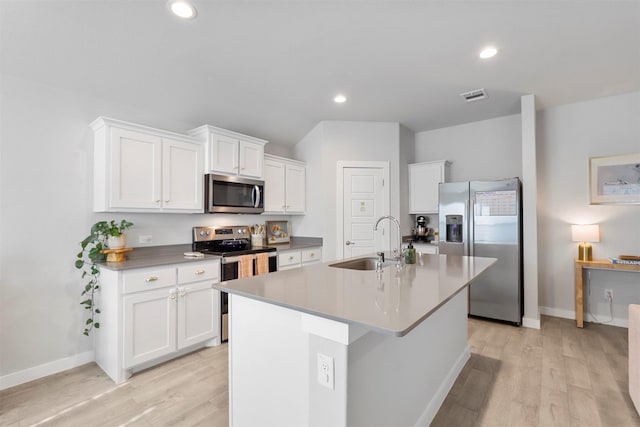 kitchen featuring stainless steel appliances, a kitchen island with sink, sink, white cabinets, and light hardwood / wood-style floors