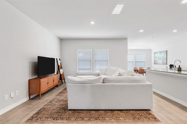 living room featuring recessed lighting, baseboards, and light wood finished floors