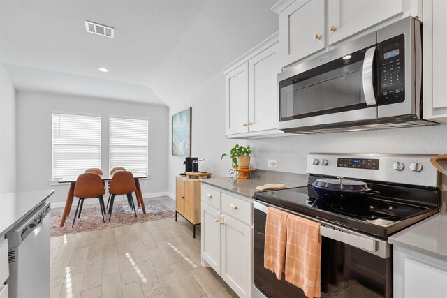 kitchen with white cabinets, stainless steel appliances, and light hardwood / wood-style flooring