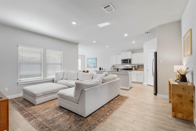 living room featuring light wood finished floors, visible vents, and recessed lighting