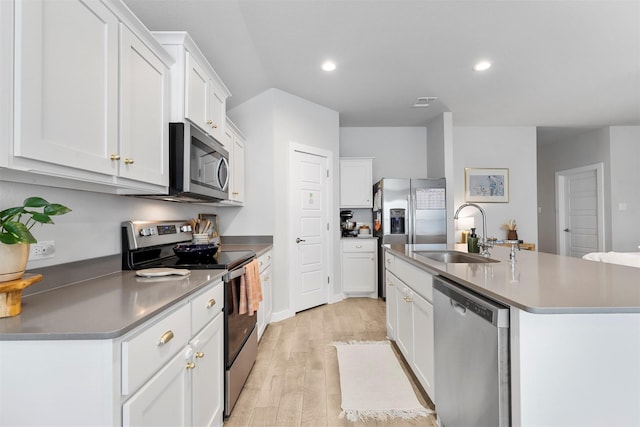 kitchen featuring a kitchen island with sink, sink, light wood-type flooring, appliances with stainless steel finishes, and white cabinetry