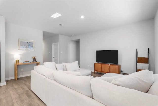 living area with light wood finished floors, recessed lighting, visible vents, and baseboards