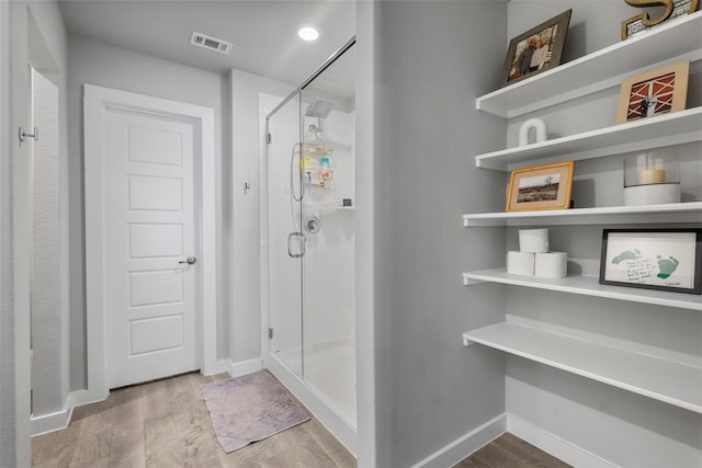 full bath featuring a stall shower, baseboards, visible vents, and wood finished floors