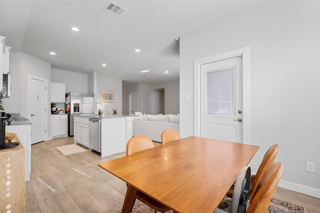 dining space with light wood-type flooring and sink