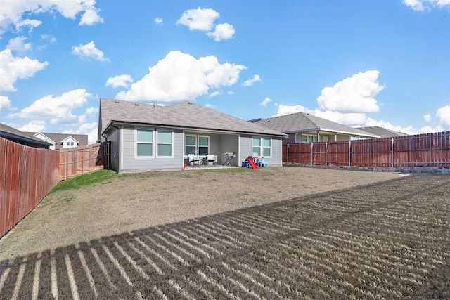 rear view of house featuring a lawn, a patio area, and a fenced backyard