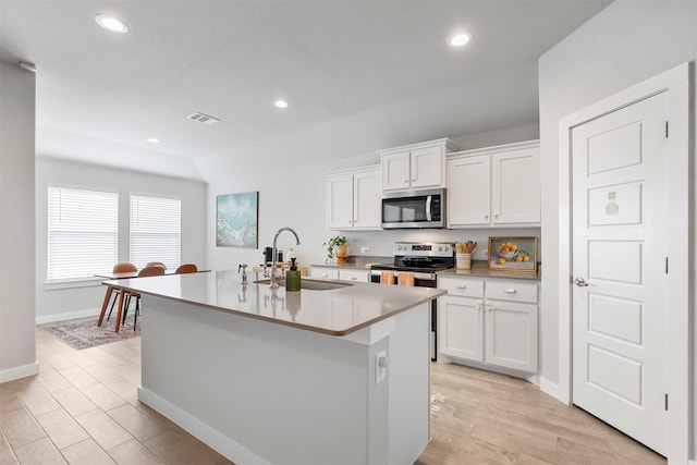 kitchen featuring white cabinets, a kitchen island with sink, sink, and appliances with stainless steel finishes