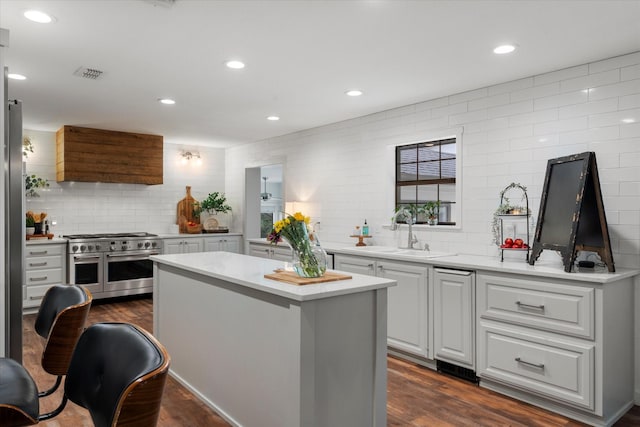 kitchen with backsplash, dark wood-type flooring, sink, double oven range, and a center island