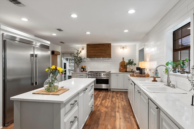 kitchen with white cabinetry, sink, high end appliances, a center island, and light stone countertops