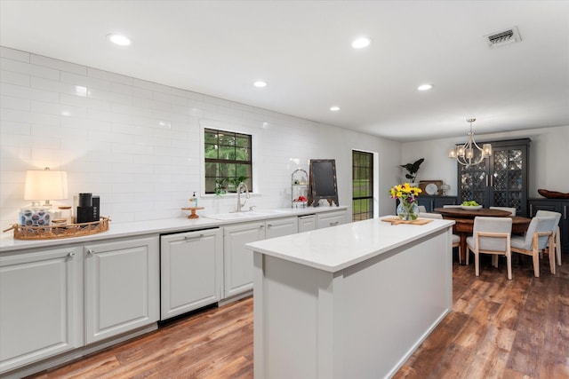 kitchen with hardwood / wood-style floors, pendant lighting, white cabinetry, dishwasher, and sink