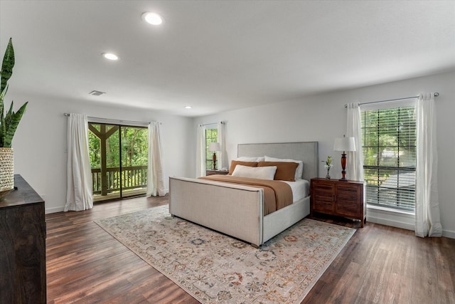 bedroom with multiple windows, dark hardwood / wood-style floors, and access to exterior