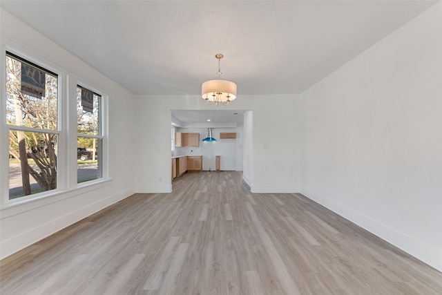 unfurnished living room with light hardwood / wood-style floors and a chandelier