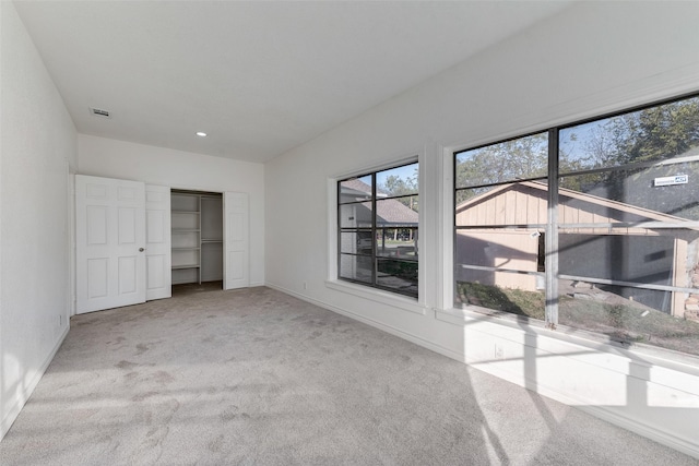 unfurnished bedroom featuring light carpet and a closet