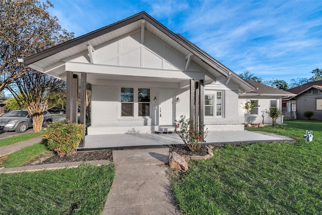 bungalow with covered porch and a front lawn